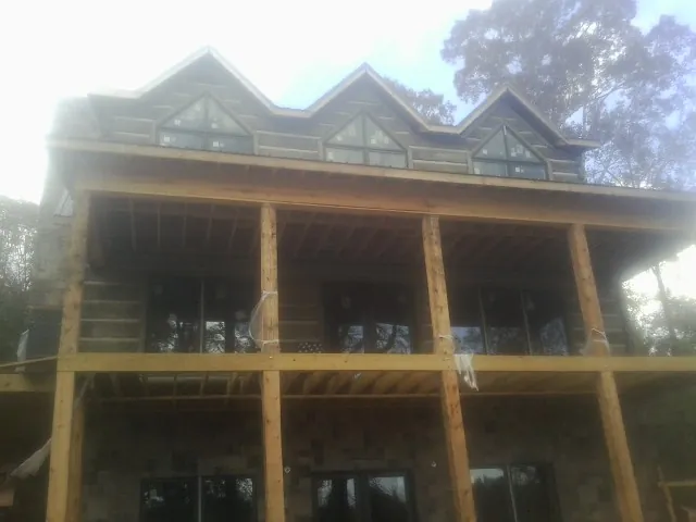 Dormers and porch framing on a large log home under construction — Roof Coating work by our crew in Auburn