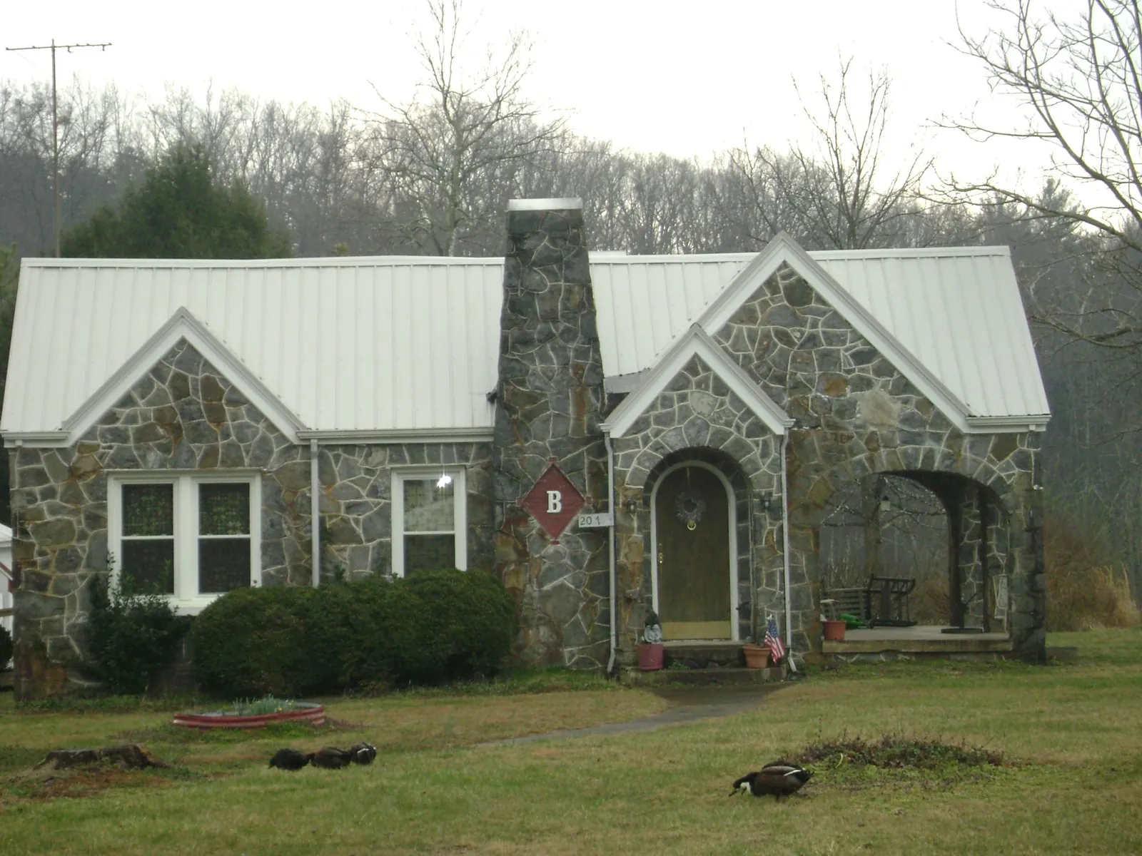 White metal roof on a stone cottage with steep gables in Auburn